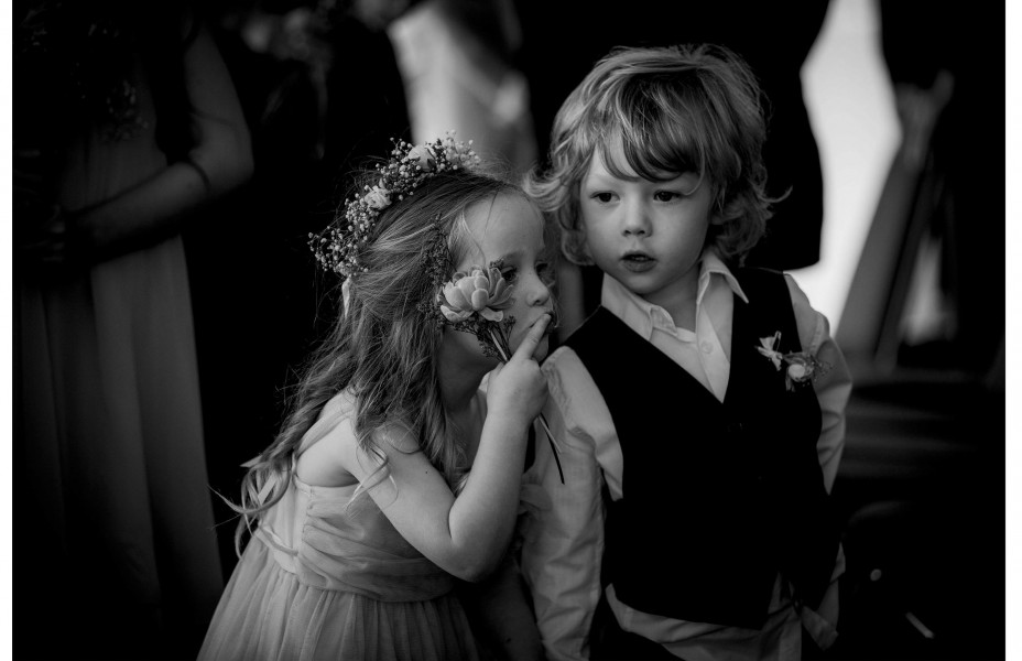 Capturing the moment.Flower girl whispers into page boys ear during wedding ceremony at Five Knots venue in Auckland.