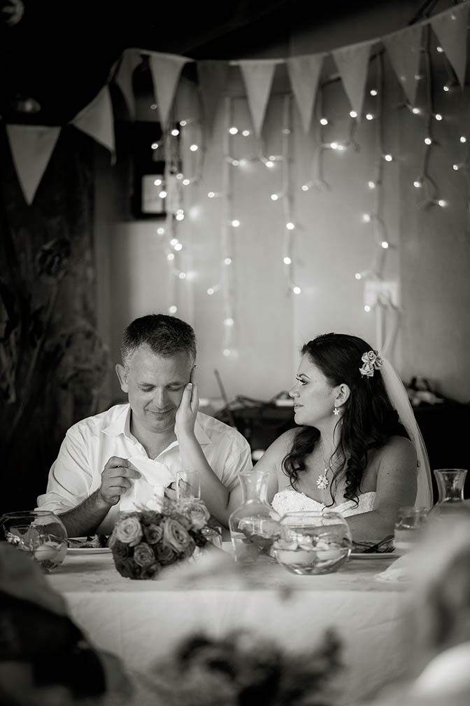 Capturing the moment. Bride touches her new husband's face with the palm of her hand in a moments gesture of loving devotion during the speeches at their wedding reception at Bethells Beach cottages.