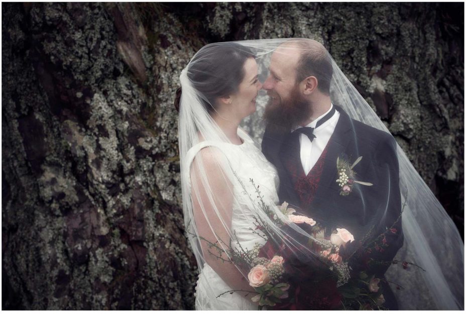 Bride and groom look into each other's eyes smiling for a wedding photo in Cornwall Park Auckland.