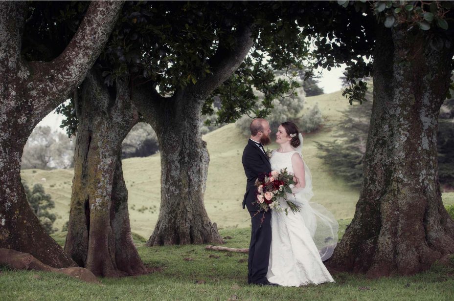 Bride and groom look into each other's eyes smiling for a wedding photo in Cornwall Park Auckland.
