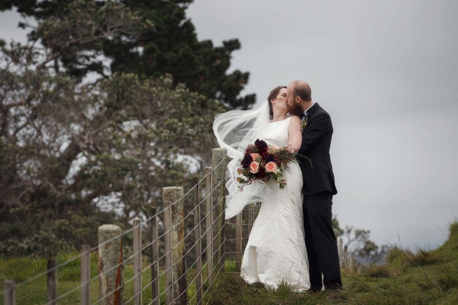 Bride and groom look into each other's eyes smiling for a wedding photo in Cornwall Park Auckland.