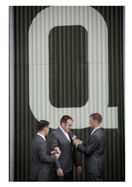 Groomsmen get ready for a wedding as they put on buttonhole flowers at Whenuapai airbase Kumeu.