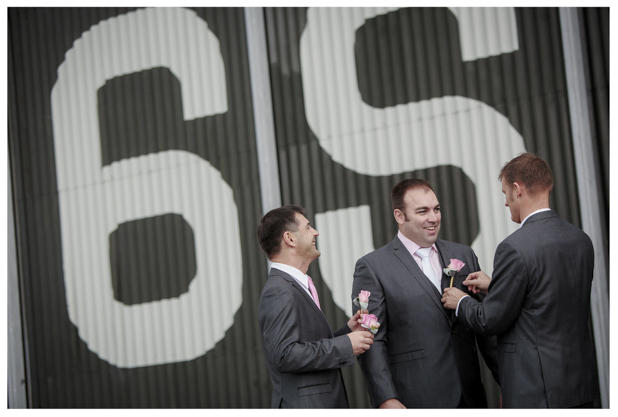 Groomsmen get ready for a wedding as they put on buttonhole flowers at Whenuapai airbase Kumeu.