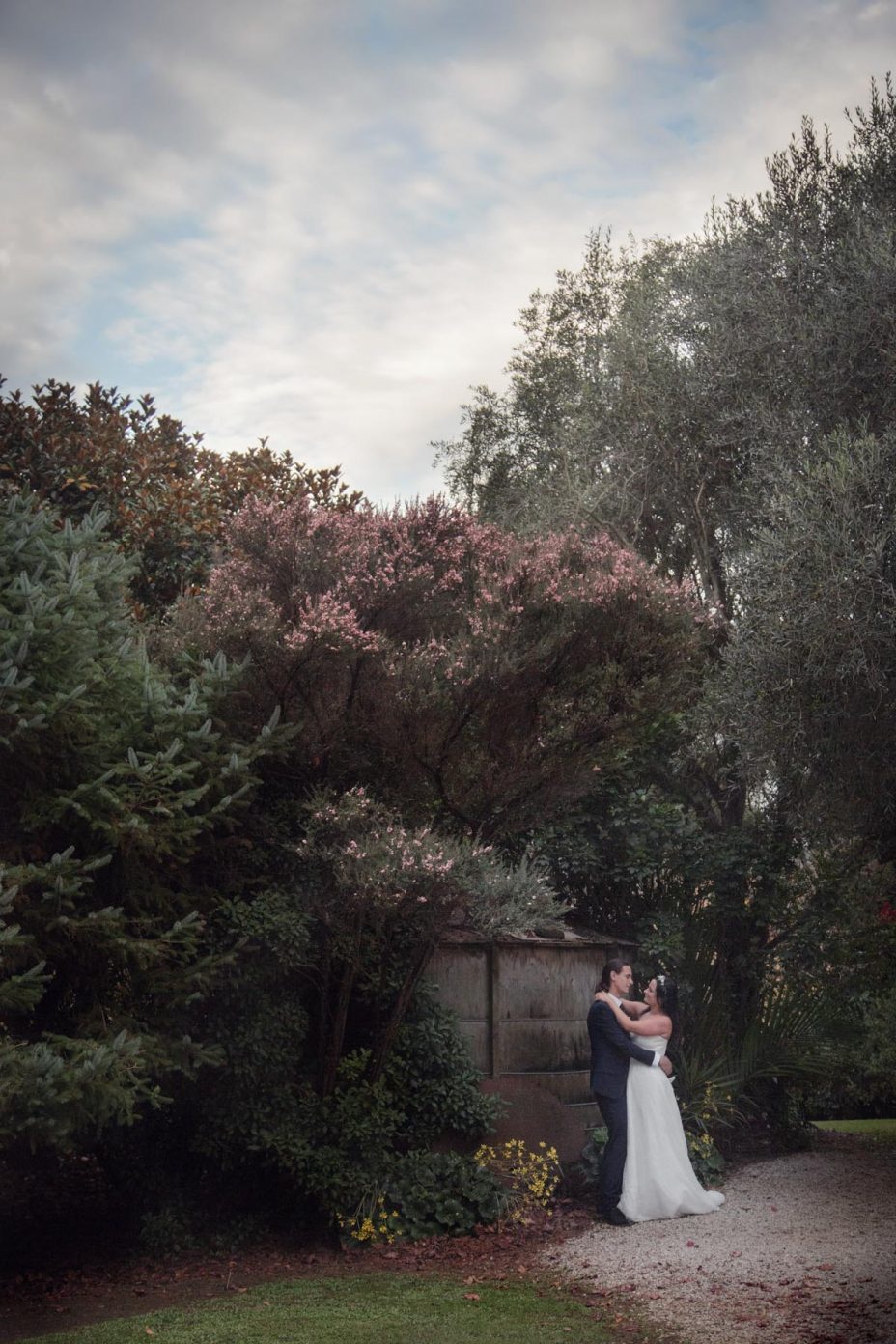 Bride and groom embrace in the garden at Kumeu Valley Estate