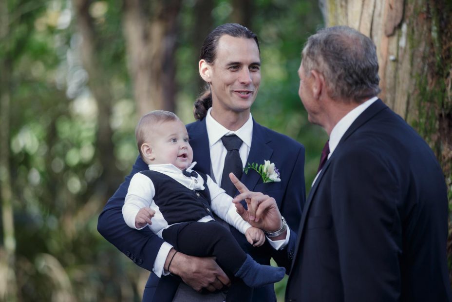 Wedding groom cradles his baby son