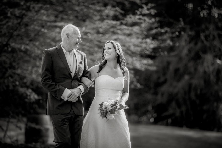 Bride laughs with her father as they walk together to her wedding ceremony