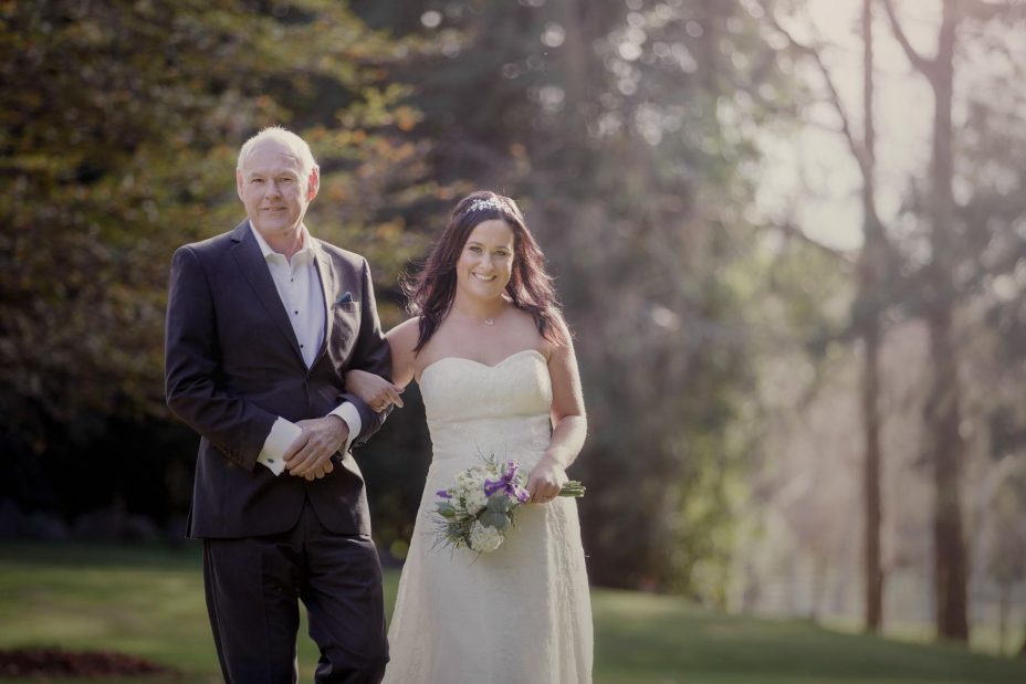 Bride laughs with her father as they walk together to her wedding ceremony