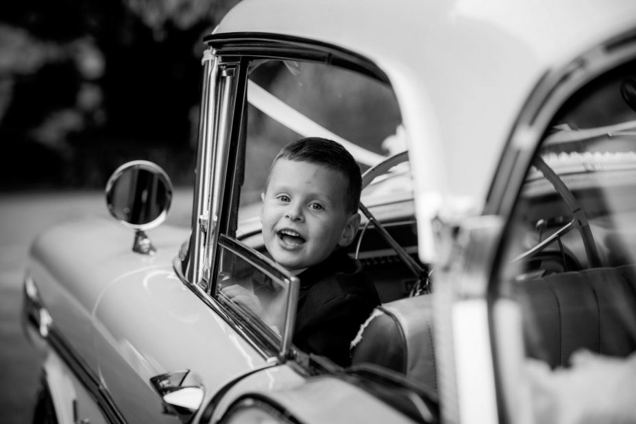 cute little boy wearing bow tie looks out of the window of Classic American car