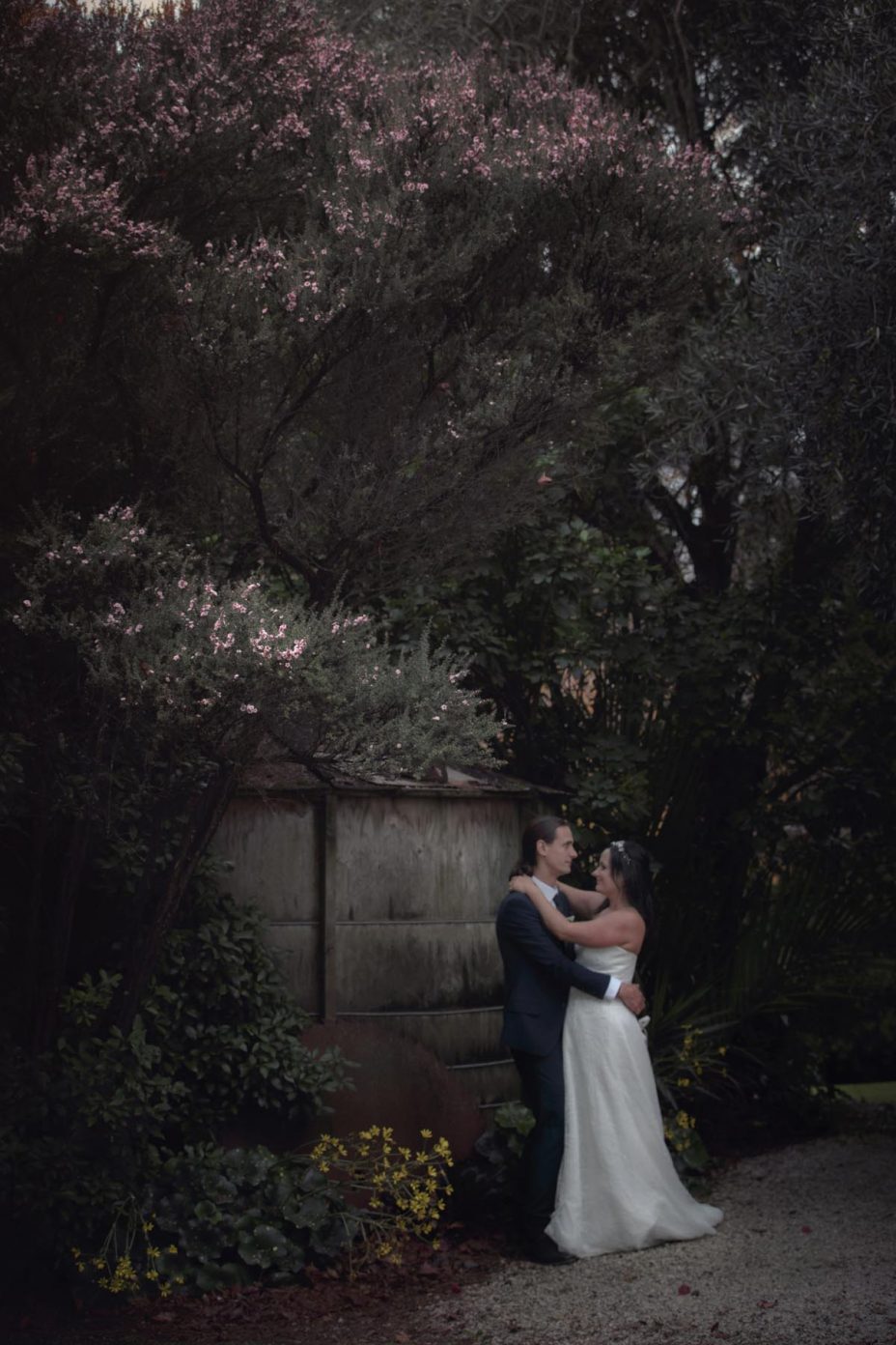 bride and groom embrace in the gardens at Kumeu Valley Estate