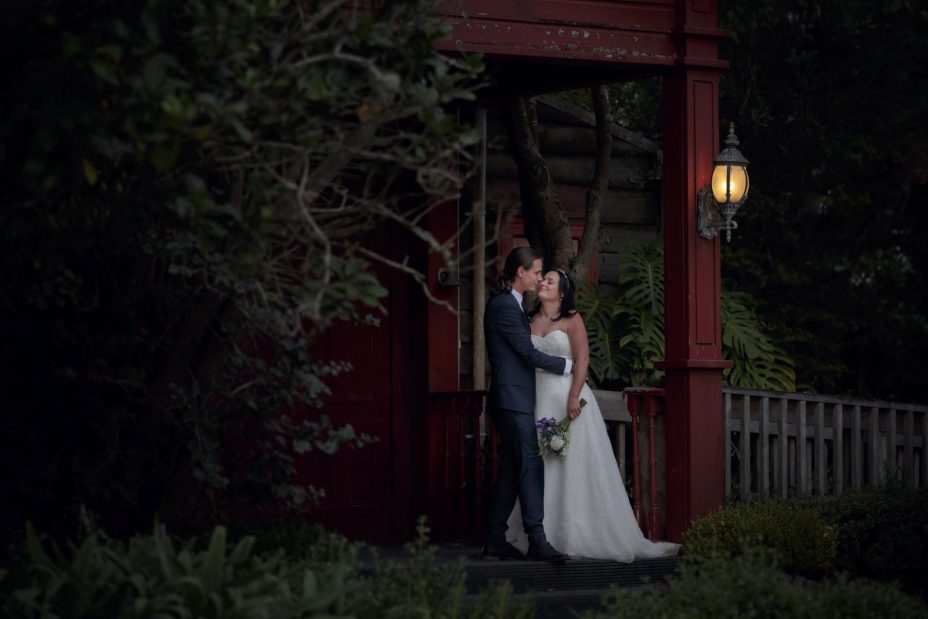 Bride and groom kiss at sunset on the front porch of Kumeu Valley Estate
