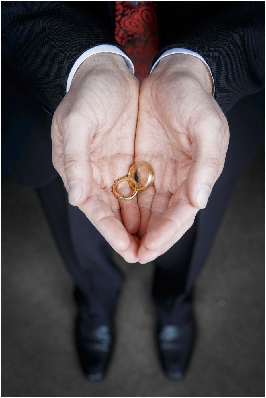 Close up photo of gold wdding rings in a man's cupped hands.