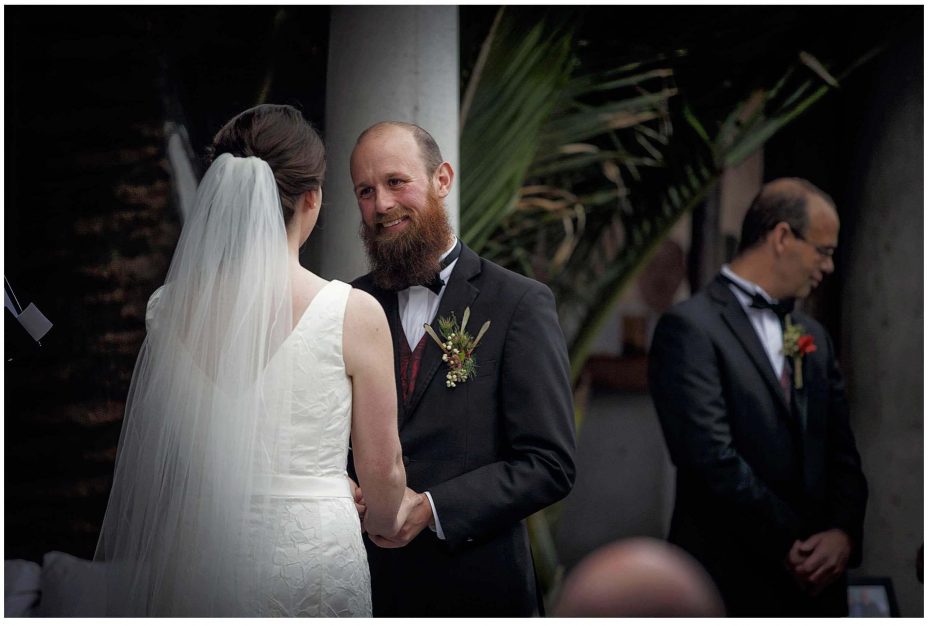 Bride and groom look into each other's eyes and smile during their wedding ceremony at Mantells Mount Eden.v