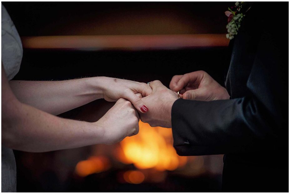 Groom places wedding ring on ring finger during wedding ceremony at Mantells Mount Eden.v