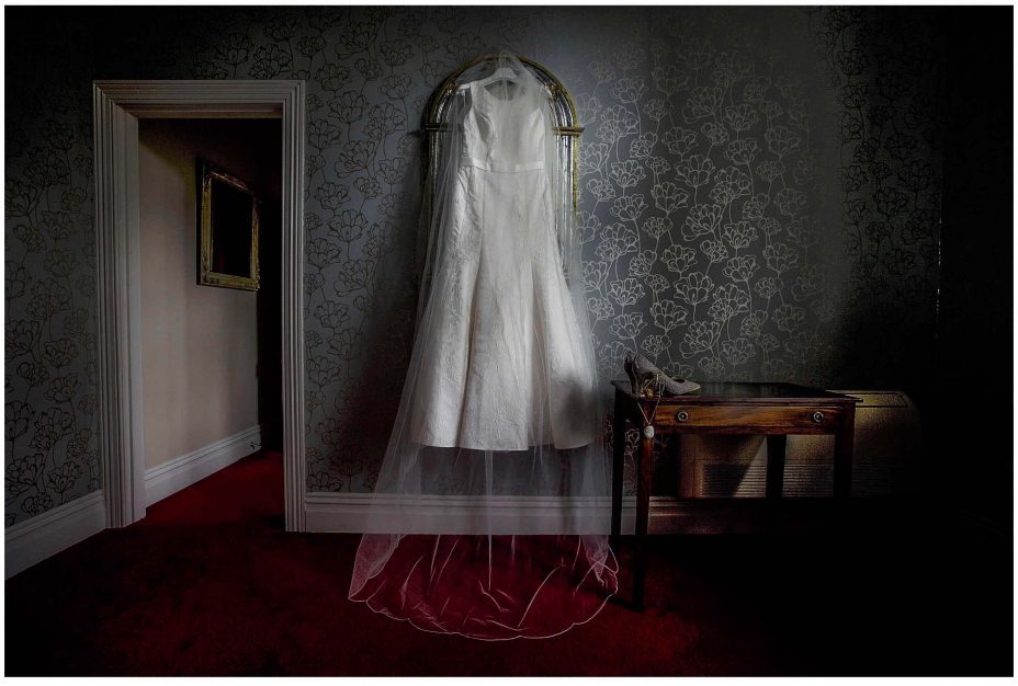 Classical white wedding dress and veil hanging from antique mirror at Mount Eden Villa.