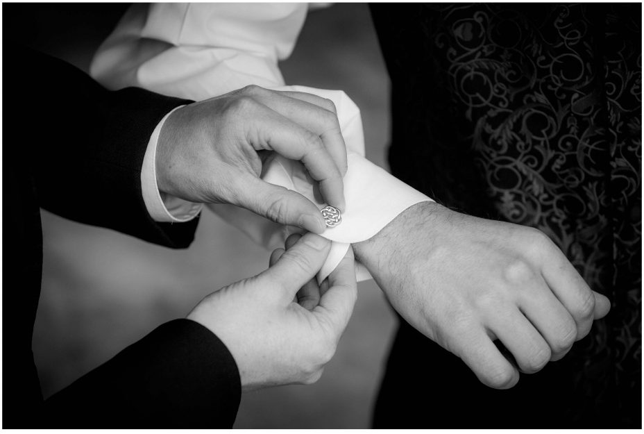 Best man helps wedding day groom put on some silver cuff-links.