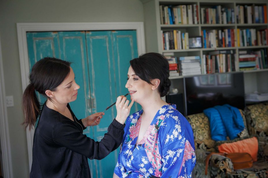 Bridesmaid wearing light blue floral kimono robe has her wedding make up applied at Mount Eden Villa.