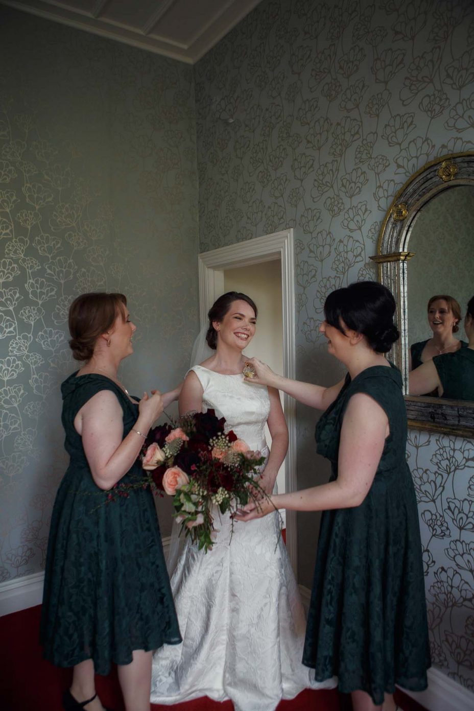 Bridesmaids spray perfume for the bride in a bedroom at Mount Eden Villa as she prepares for her wedding