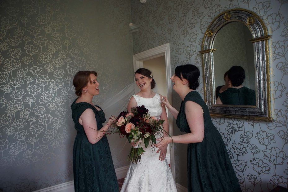 Bridesmaids spray perfume for the bride in a bedroom at Mount Eden Villa as she prepares for her wedding