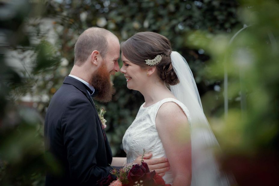Wedding day groom smiles happily as his bride to be as she reveals herself in her wedding dress for the first time in the garden at Mount Eden Villa.