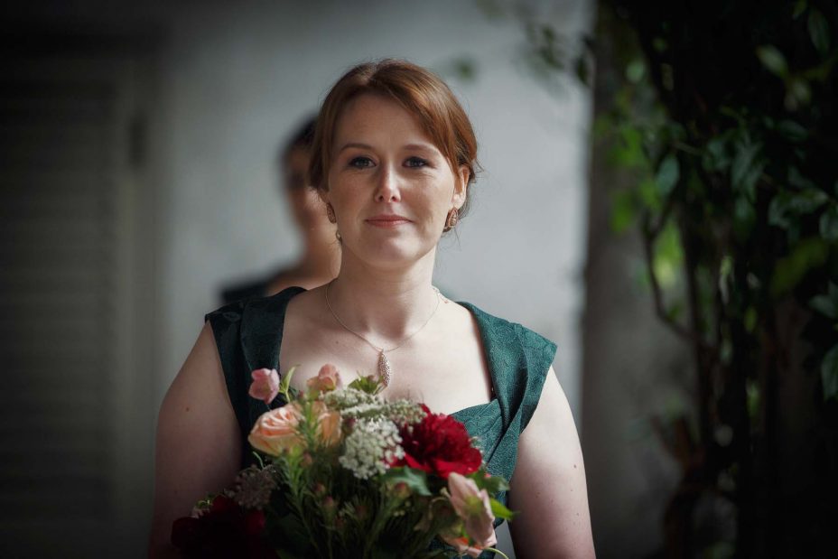 Bridesmaid looks directly into the camera as she walks towards the wedding ceremony at Mantells in Mount Eden.