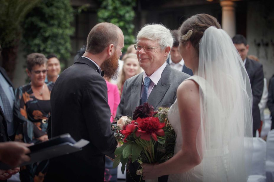Brides father shakes the grooms hand as he gives him his daughter to marry at their wedding ceremony at Mantells in Mount Eden.
