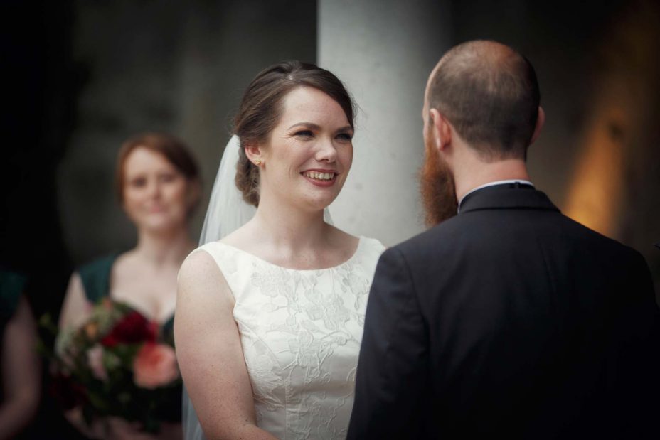Smiling happy bride looks into the grooms eye's during their wedding ceremony .