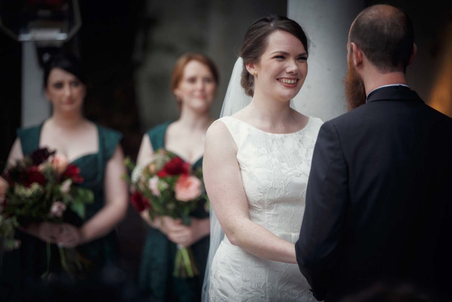 Smiling happy bride looks into the grooms eye's during their wedding ceremony .
