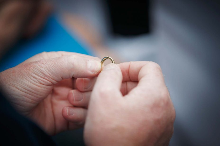 Close up photo of one of the guests holding the bride's gold wedding ring.