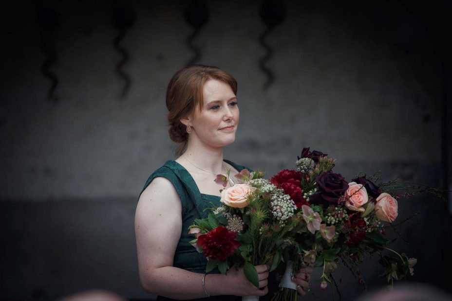 Bridesmaid holds the bride's wedding flowers during the ceremony at Mantells in Mount Eden.