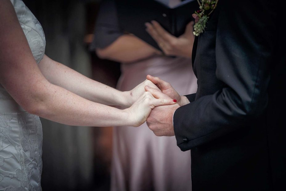 Close up photo of bride and groom hold hands during their wedding ceremony at Mantells Mount Eden.