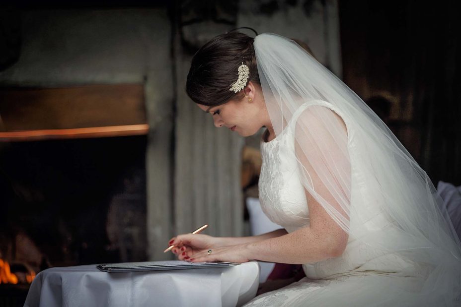 he bride sits and completes the wedding register following the ceremony at Mantells in Mount Eden.