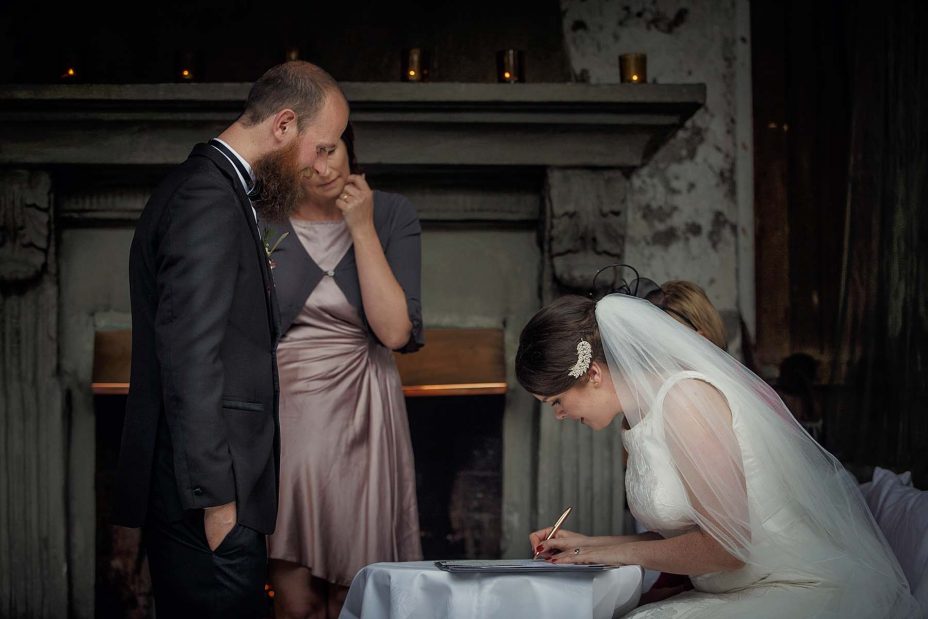he bride sits and completes the wedding register following the ceremony at Mantells in Mount Eden.