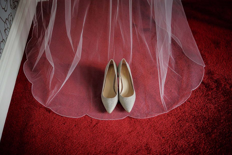 Bride's wedding shoes framed by her viel on a red carpet at Mount Eden Villa.