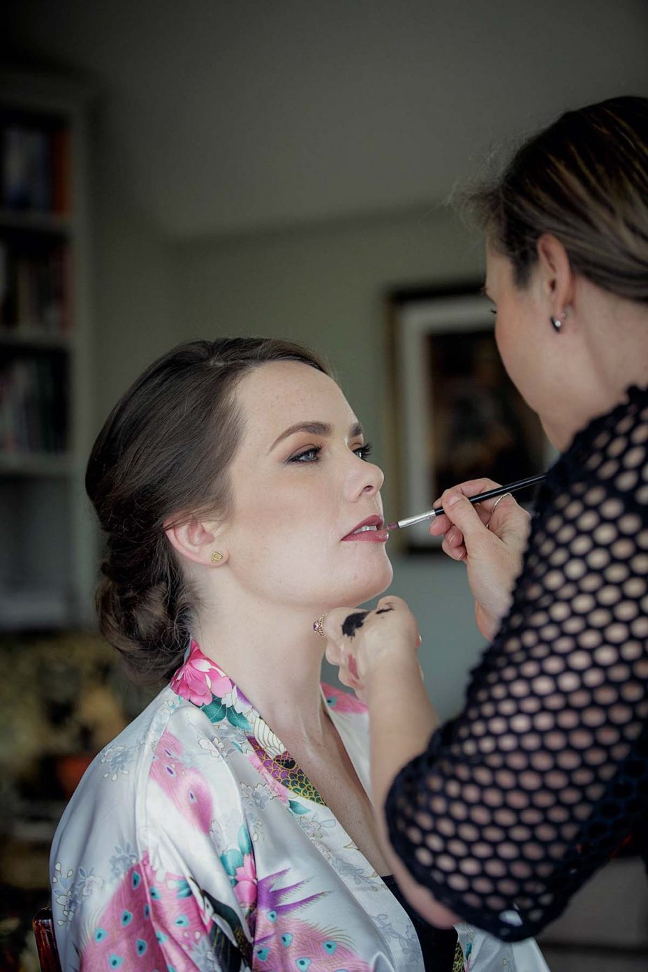Wedding day floral kimono robe has her wedding make up applied at Mount Eden Villa.
