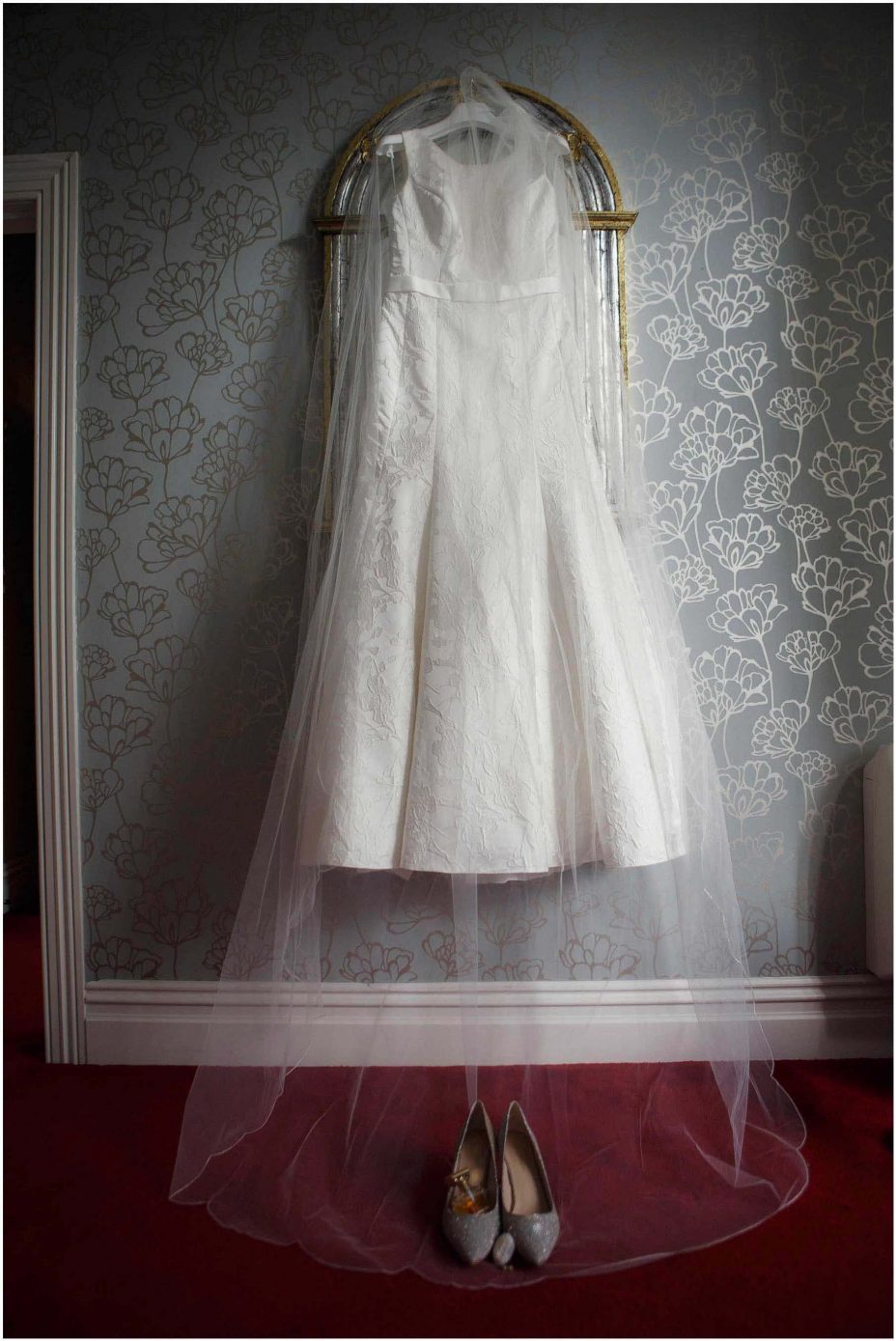 Classical white wedding dress and veil hanging from antique mirror at Mount Eden Villa.