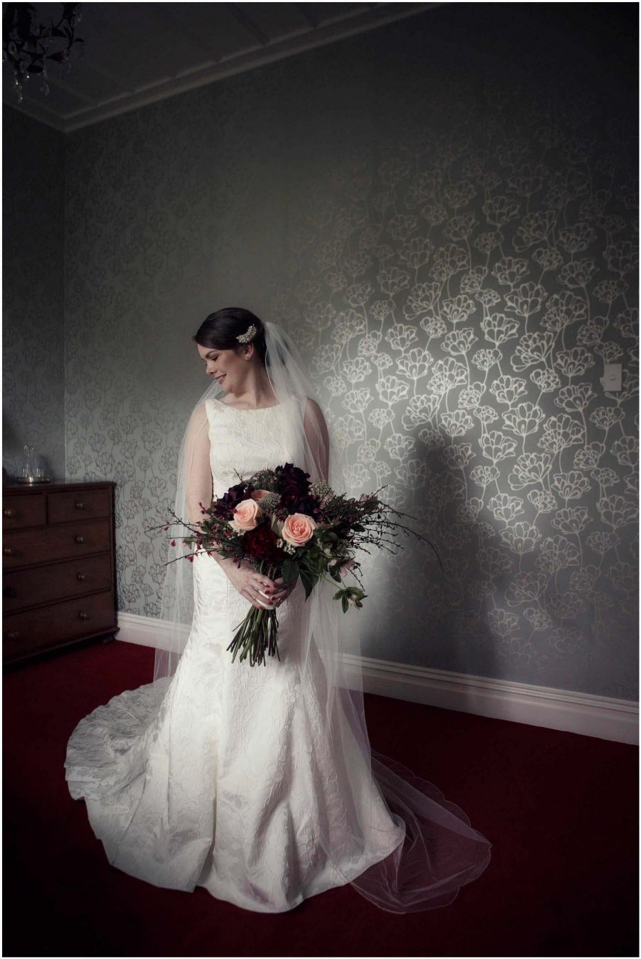 Bide wearing classical white wedding dress with train holding floral bouquet at Mount Eden Villa