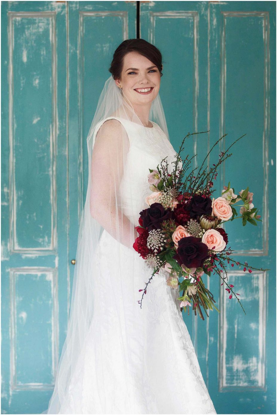 Bide wearing classical white wedding dress with train holding floral bouquet at Mount Eden Villa
