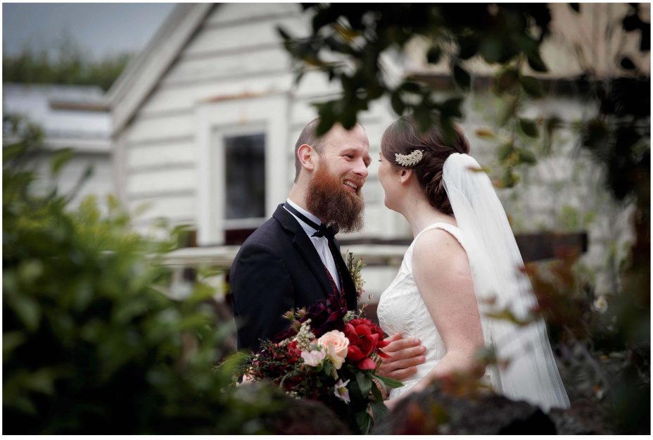 Wedding day groom smiles happily as his bride to be as she reveals herself in her wedding dress for the first time in the garden at Mount Eden Villa.