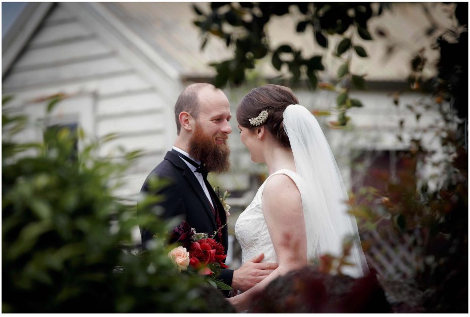 Wedding day groom smiles happily as his bride to be as she reveals herself in her wedding dress for the first time in the garden at Mount Eden Villa.
