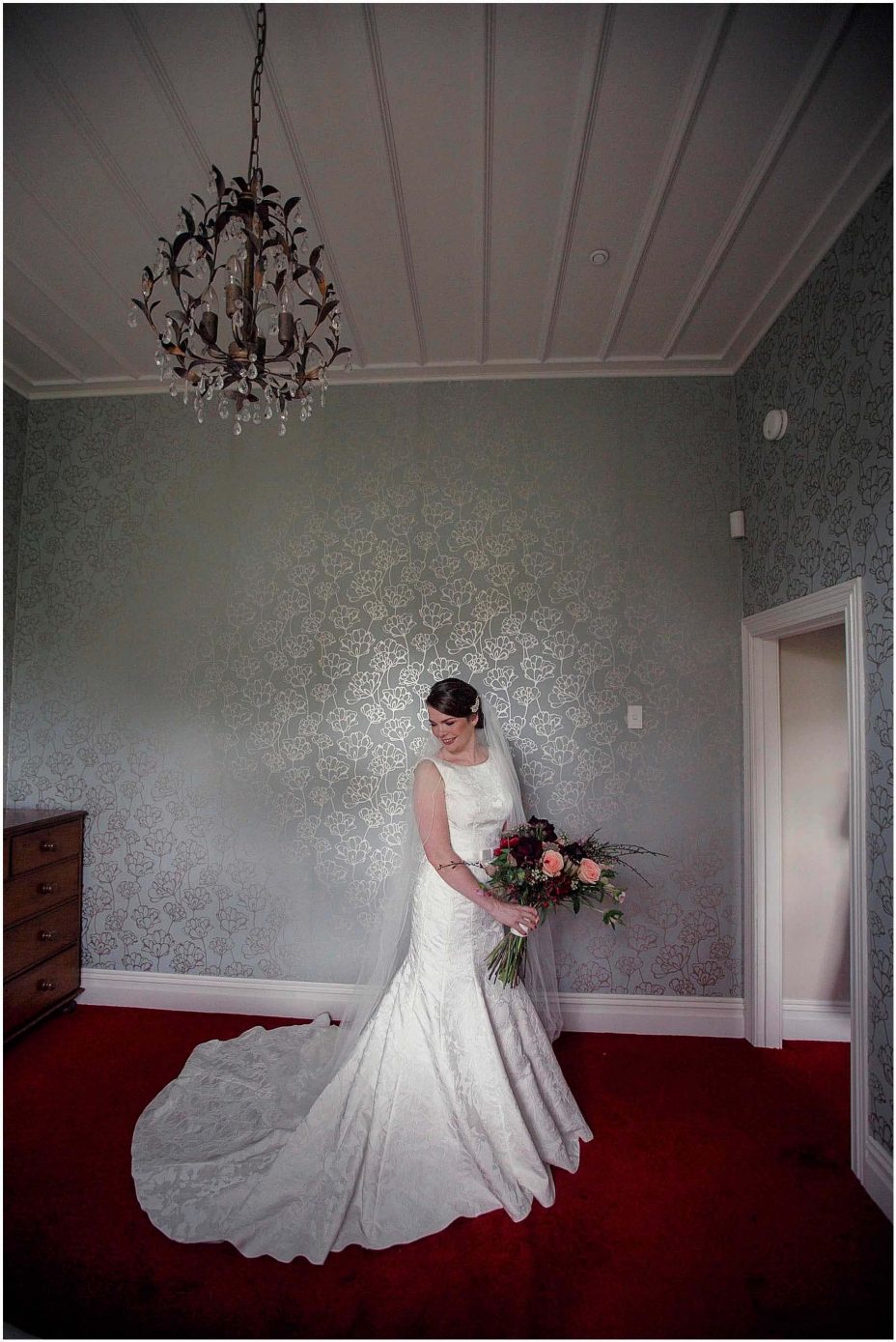 Bide wearing classical white wedding dress with train holding floral bouquet at Mount Eden Villa