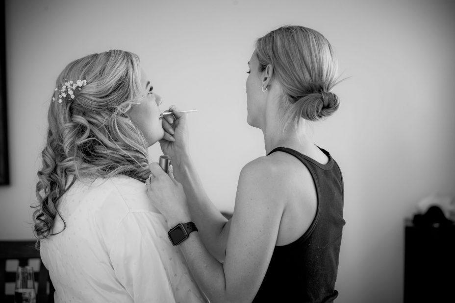 black and white photo of bride having her wedding make up applie