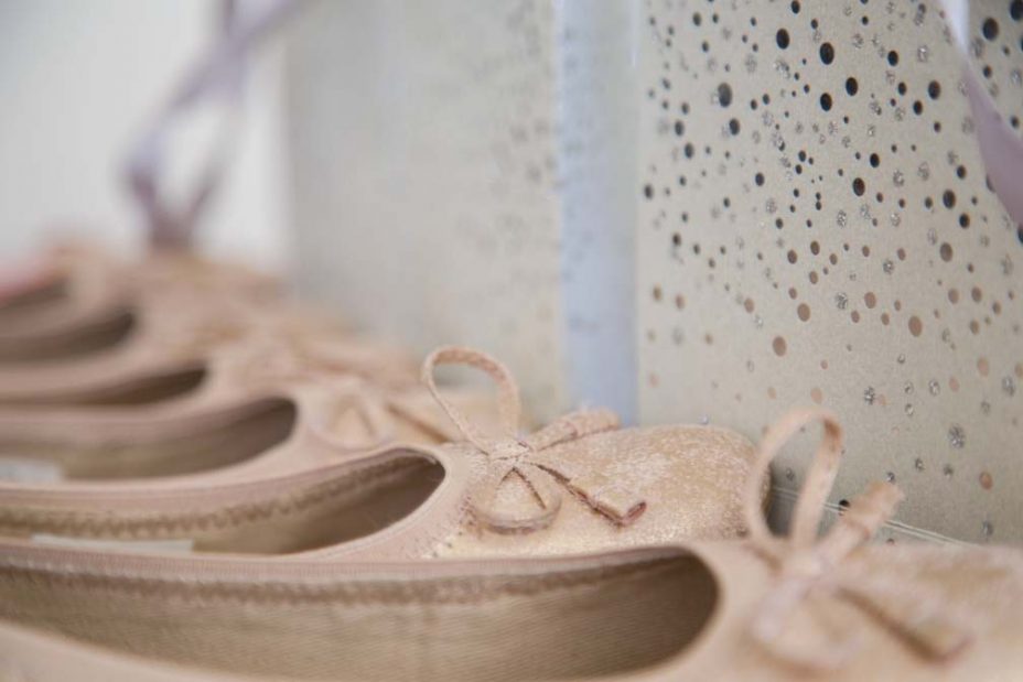 flower girls matching pink slip on shoes with bows on the toes and a unicorn hairbrush sit side by side with three gift bags containing jewellery. Wedding photos at Fort Takapuna and the Officers Mess in Auckland.