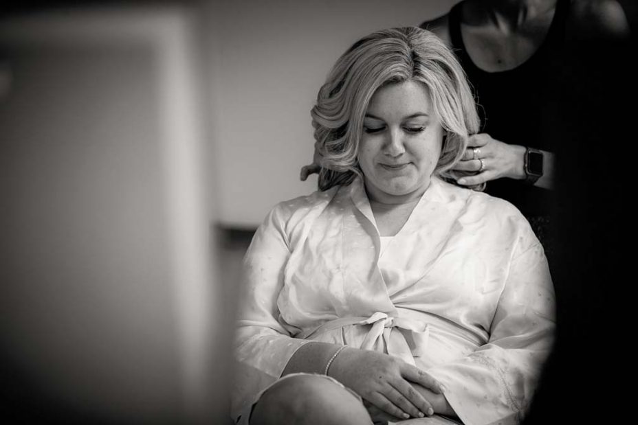 Black and white photo of a wedding day bride discussing hairstyles with has makeup artist as they get ready for her wedding ceremony and reception at Fort Takapuna and the Officers Mess in Auckland.