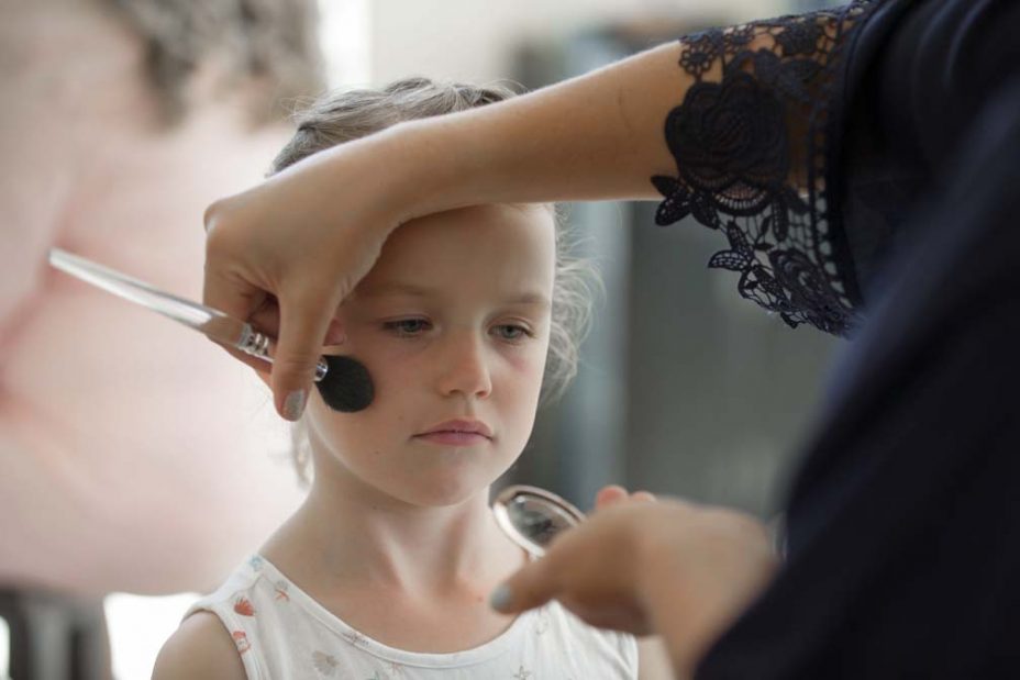 Little flower girl has some eye make up applied during bridal preparations before a wedding at FortTakapuna and the Officers Mess in Auckland.