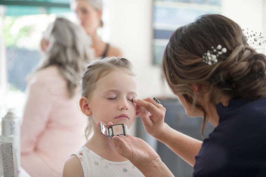 Little flower girl has some eye make up applied during bridal preparations before a wedding at Fort Takapuna and the Officers Mess in Auckland.