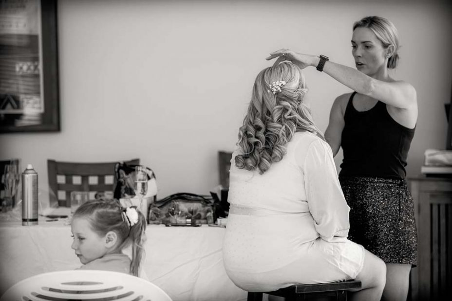 The bride wearing a pink robe has her make up applied as she prepares for her wedding at Fort Takapuna and the Officers Mess in Auckland.