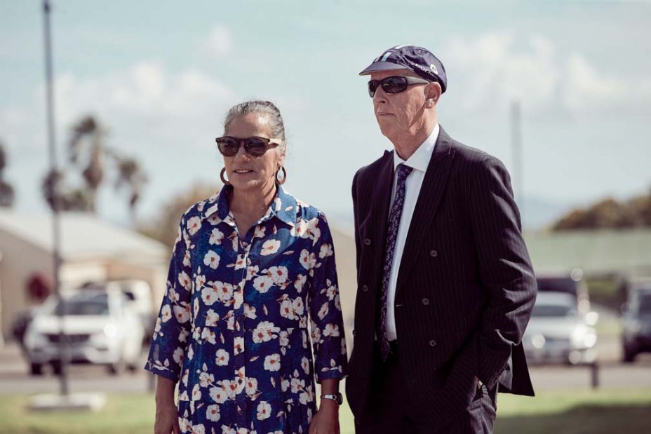 Wedding guests laughing in the sunshine following a wedding ceremony at Fort Takapuna in Auckland.